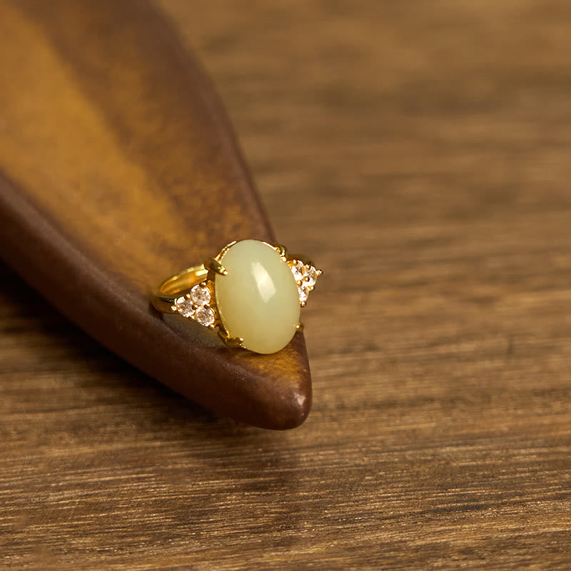 Hetian jade egg ring rested on wooden scoop displaying smooth matte gold finish and solid jade center stone