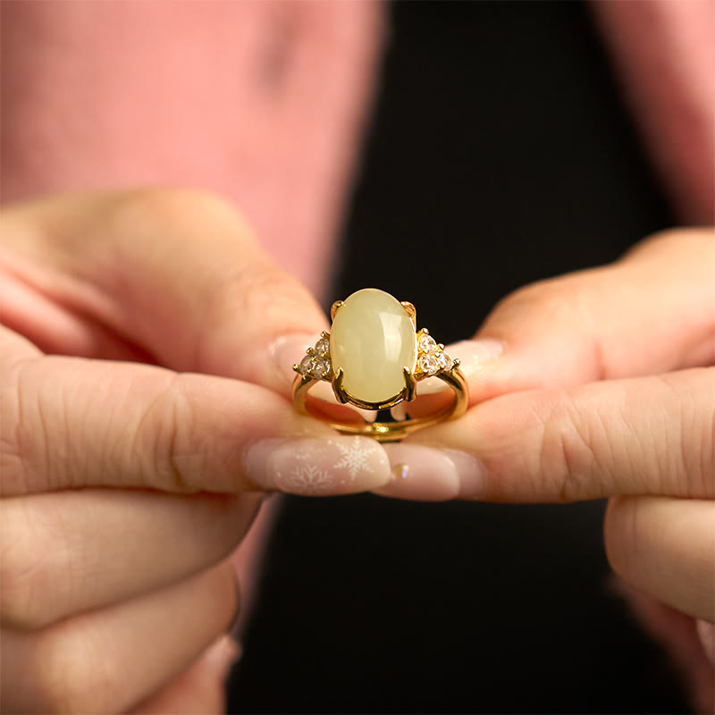 Hand-held close-up of Hetian jade egg ring held between fingertips showcasing smooth jade surface and elegant design
