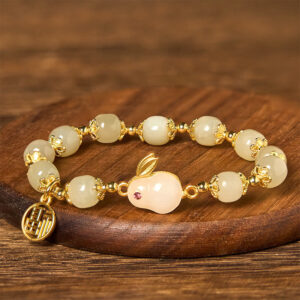 Close-up angled view of jade beads and rabbit charm with red ruby eye and gold fu pendant