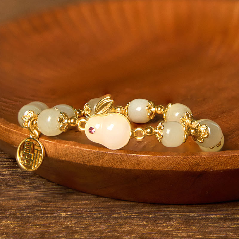 Side profile of hetian jade bracelet showing round polished beads and metal fu character pendant