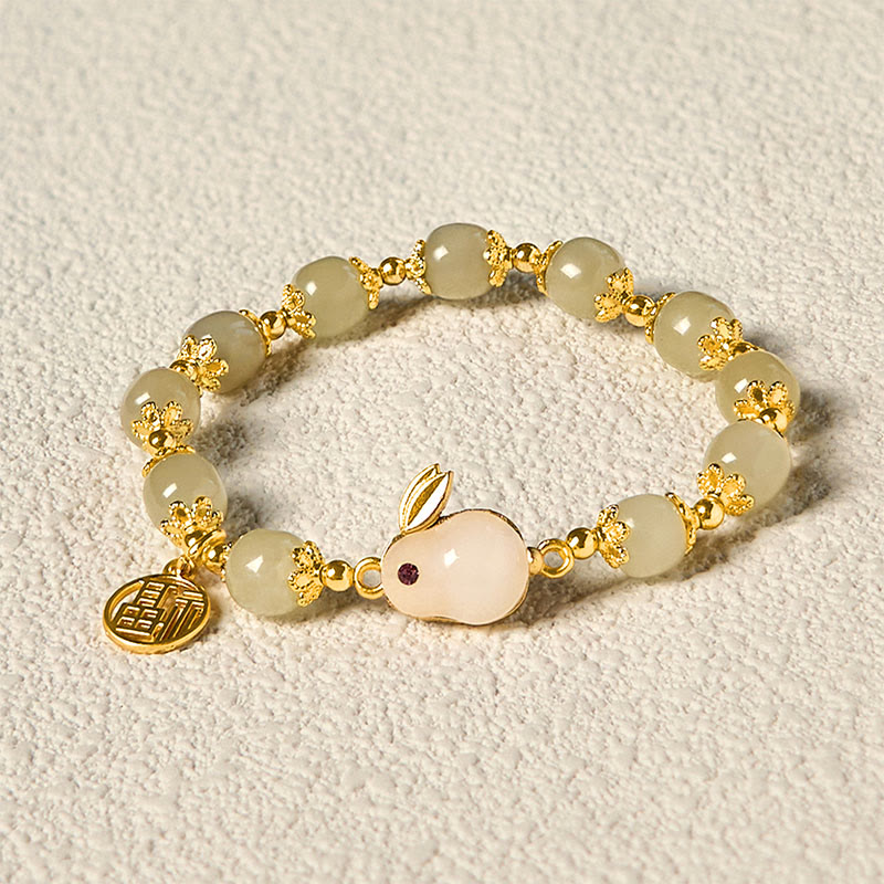 Hetian jade rabbit blessing bracelet displayed on neutral surface with gold accents visible