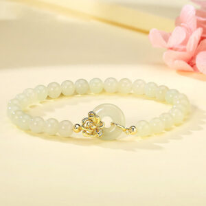 Hetian jade peace buckle bracelet with 925 sterling silver clasp, displayed with pink flowers, showing pale green beads and traditional Chinese knot design