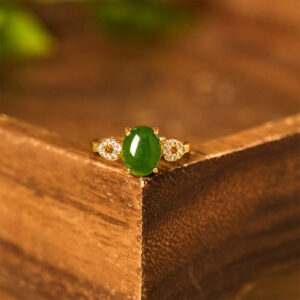 Close-up top-down view of jade ring showing oval green stone center with decorative diamond side settings on gold band