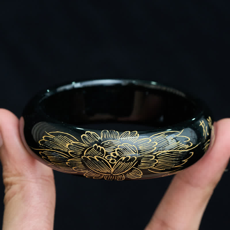 Authentic cyan jade bangle bracelet with traditional gold-inlaid floral design, top-down handheld view