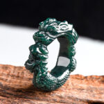 Cyan jade dragon carved ring shown in high side perspective view displaying emerald green jade with intricate dragon carving and scaled surface texture