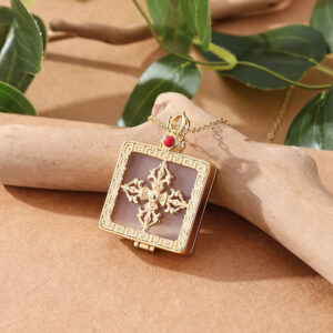Double dorje white jade pendant necklace worn on hand, side angle view displaying translucent white jade and polished gold-plated frame with red gem ornament