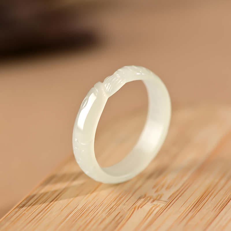 White Hetian jade koi fish ring flat lay showing milky white polish with intricately carved koi design on light wooden surface