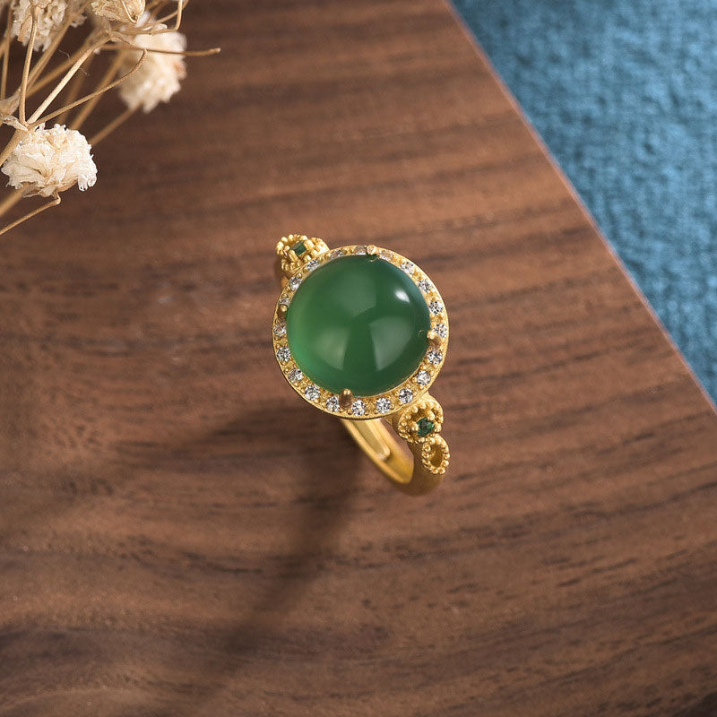 Adjustable green jade ring with ornate gold band details and accent stones oblique view