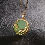 Cyan jade koi fish lotus pendant necklace with gold embossed frame close-up view on dark background