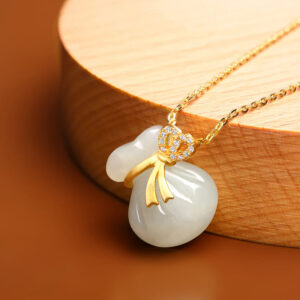 Authentic Hetian white jade prosperity necklace pendant displayed on wooden round base, showing carved purse design with golden ribbon