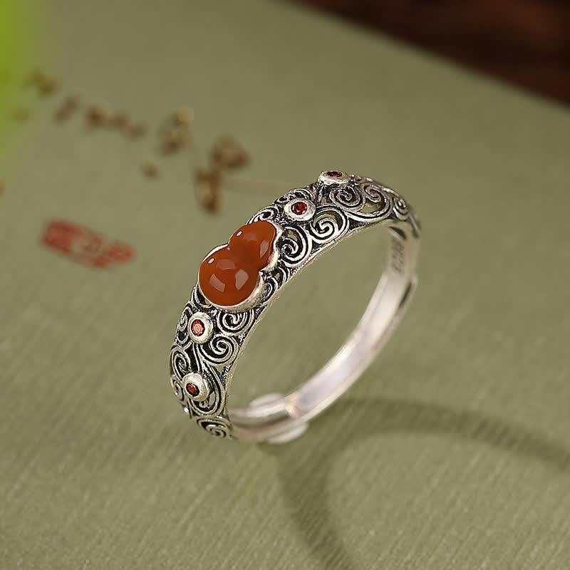 Red agate sterling silver gourd ring with adjustable open band showing side detail and carved scroll pattern