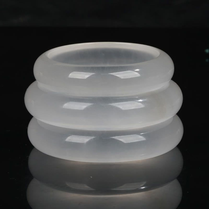 Stacked white translucent jade bangles in front flat lay arrangement showing uniform glossy finish on dark studio background