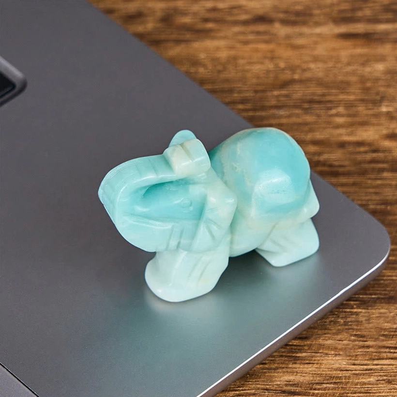Hand-carved amazonite elephant figurine displayed on laptop edge for size comparison