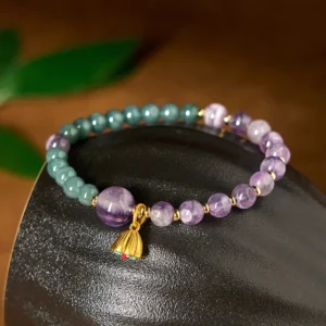 Purple amethyst and green jade beaded bracelet close-up with gold lotus pendant detail