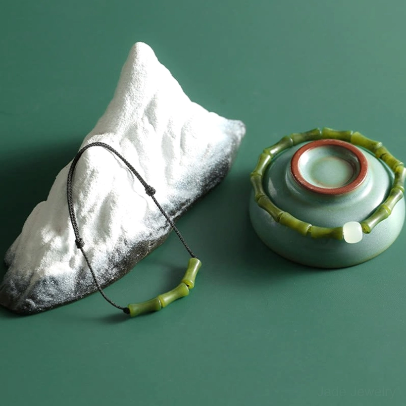 Flat lay overhead view of green bamboo jade bracelet with black woven rope cord and white jade centerpiece bead