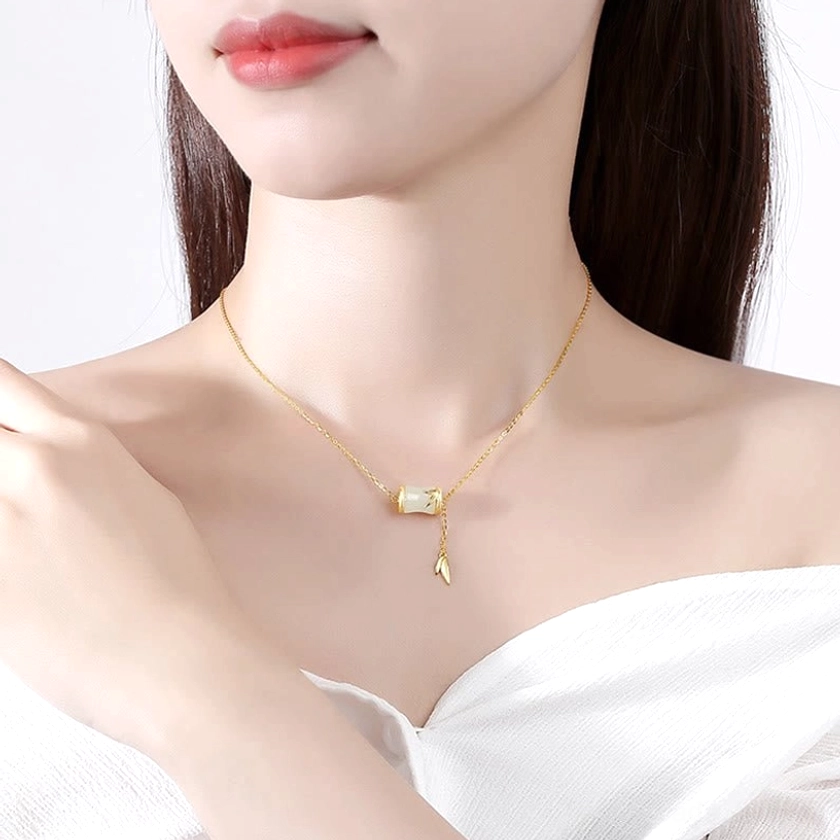 Woman wearing delicate gold-toned bamboo jade necklace at collarbone, lifestyle portrait showing how the handcrafted Y-lariat necklace sits elegantly on the décolletage with jade bamboo charm visible