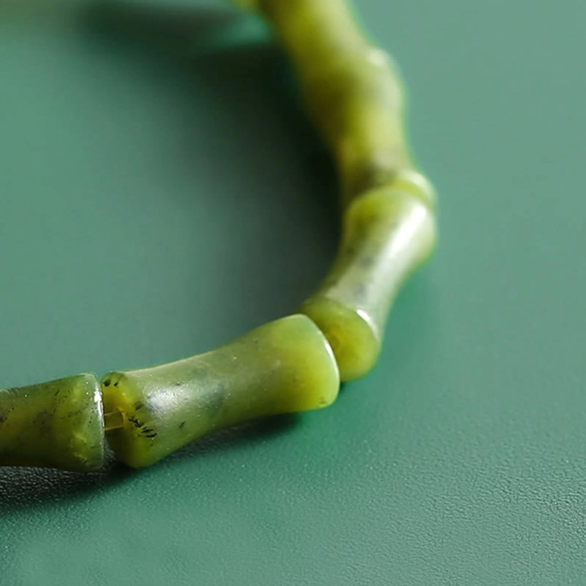 Detailed macro shot of carved bamboo joint pattern on green jade bead showing natural stone veining