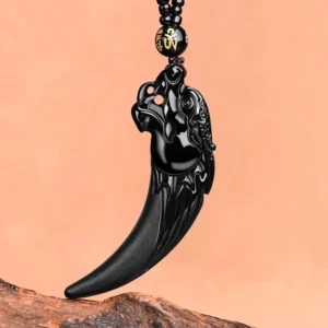 Black jade dragon tooth protection necklace pendant with hand-carved dragon head design, glossy polished finish on tan background