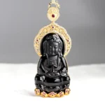 Black jade Kwan Yin pendant front view with ornate gold frame and red gem accents on minimalist background