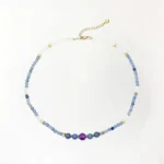 Blue aventurine white jade amethyst beaded necklace with gold spacers on white background, top-down view showing full strand and adjustable chain