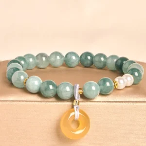 Blue jade peace buckle beaded bracelet with white pearls and yellow jade pendant displayed on beige jewelry tray, featuring gradient green jade beads