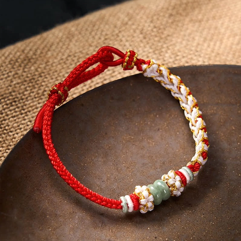 Braided jade luck bracelet with green peach blossom knot on ceramic tray