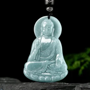 Amitabha Buddha jade amulet angled frontal view showcasing detailed Buddha carving and matte jade texture with natural stone and foliage background