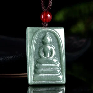 Green jade Buddha amulet pendant suspended on cord with natural foliage background