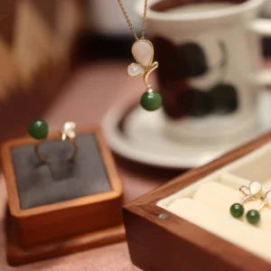 Coordinated butterfly jade jewelry collection shown in close-up detail with gold-plated metal and mother-of-pearl elements on styled tabletop