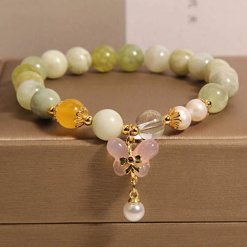 Butterfly jade prosperity bracelet with serpentine jade beads and golden agate in brown leather jewelry box, overhead flat lay view