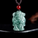 Natural green jade Caishen God of Wealth pendant necklace with brown cord and red accent bead - front view on black display