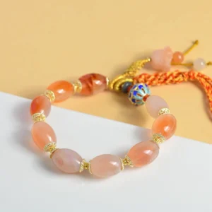 Candy agate jade beaded bracelet flat lay with enamel charm and red woven tassel on yellow background