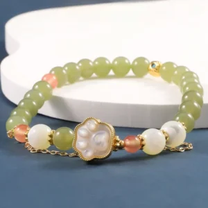 Cat paw charm jade bracelet close-up on white ceramic display stand, showing detailed green jade beads and gold-framed cat paw decoration with layered chain detail