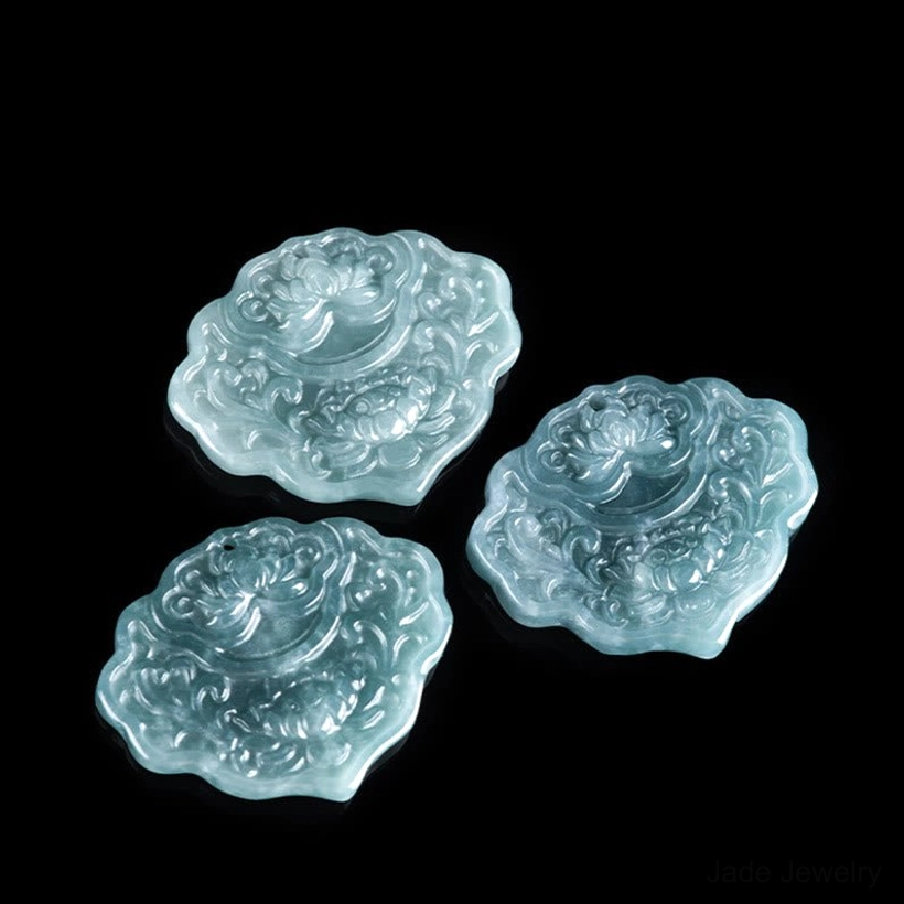 Three loose celadon jade pendants with identical lotus scroll carving design flat lay