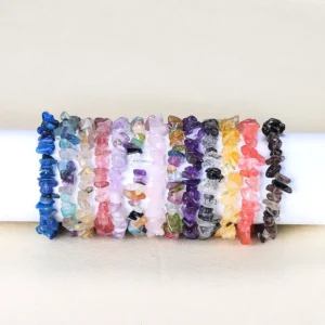 Mixed irregular crystal stone bracelet collection displayed on white display rod, showing multiple colorful natural gemstone varieties
