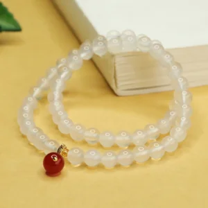 Side angle view of white chalcedony beads with red agate pendant charm on beaded bracelet