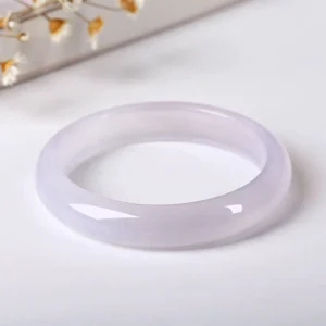 Natural chalcedony bangle bracelet with smooth polished finish in pale lavender translucent stone, top-down flat lay view