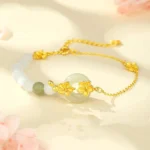 Chrysoberyl hetian jade peace bracelet with floral charm in gold-plated silver, overhead flat lay on pastel floral background