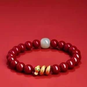 Cinnabar Hetian jade snake blessing bracelet with glossy red beads, white jade, and gold snake charm on deep red background