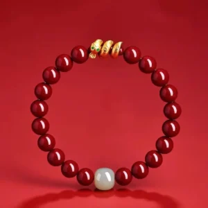 Top-down flat lay of cinnabar jade snake bracelet showing full circular design with gold decorative accents and white jade center bead