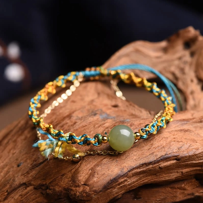 Handmade jade bead bracelet with colorful braided rope and decorative tassel, flat lay style