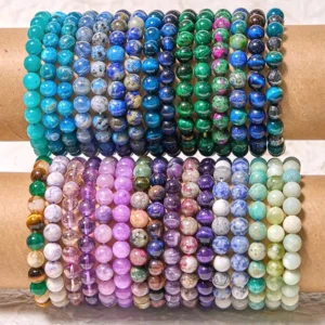 Multiple cool-tone crystal healing bracelets in flat lay arrangement featuring blue tiger eye, amethyst, aquamarine, jade and mixed gemstones
