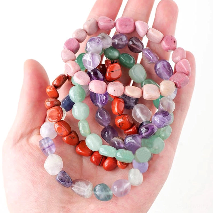 Hand holding multi-color tumbled natural stone crystal bracelet showing elastic fit design and stone variety