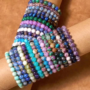 Stacked cool-tone healing bracelets worn on wrist showing blue, purple, and green crystal beads for tranquility and emotional balance