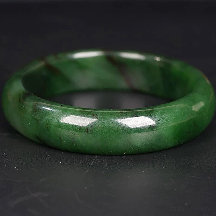 Cyan jade bangle flat lay showing dark vein inclusions authentic nephrite