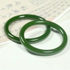 Two matching cyan jade bangle bracelets showing identical emerald green color and slim round design