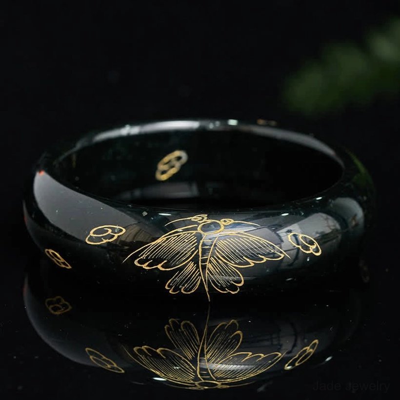 Polished cyan jade bangle bracelet with cloud and insect motifs reflecting light on glossy surface