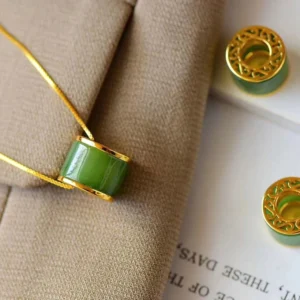 Cyan jade barrel pendant necklace with gold trim, close-up top view showing polished jade stone detail on khaki fabric