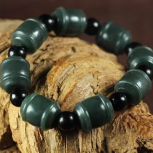 Authentic cyan jade bracelet showing alternating jade and black round spacer beads in neat arrangement, side overhead perspective on rustic wood surface
