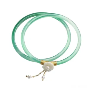 Pair of polished cyan jade bangles in overhead flat lay with matching decorative accessories